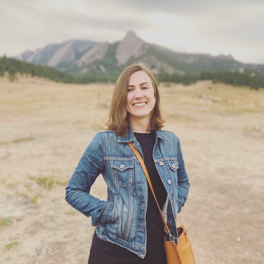 A picture of myself with short brown hair against the background of the Flat Iron mountains in Boulder, Colorado.